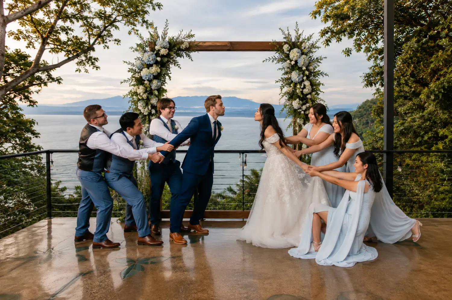 A long banquet table dressed in white linen facing the sea at dusk.